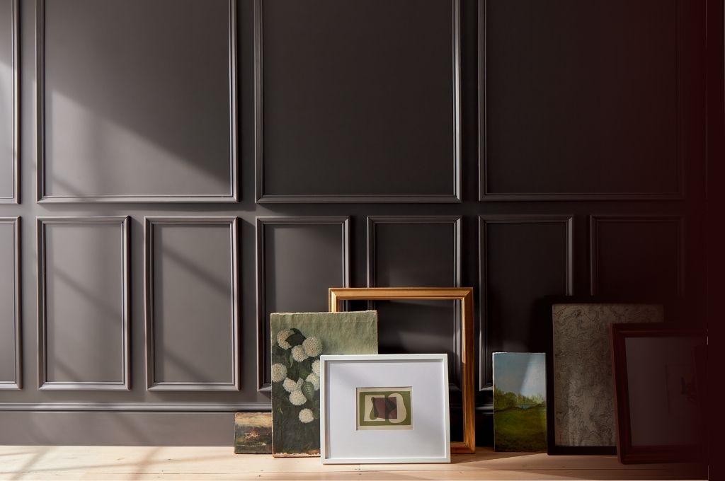 Framed artworks on a wooden surface against a dark paneled wall. Benjamin Moore 2026 Color of the year Silhouette AF-655