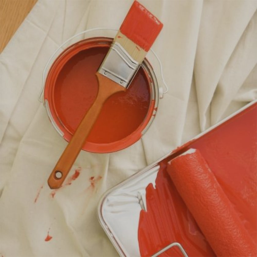 paint can with paint brush, tray & tray liner and roller on a drop cloth