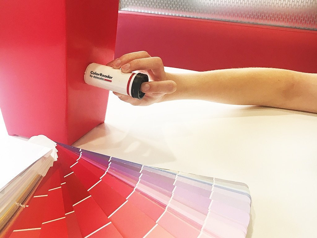 A person using the Datacolor Color Reader on a red object to determine the closest paint color match, available at Mallory Paint Store in WA &amp; ID.